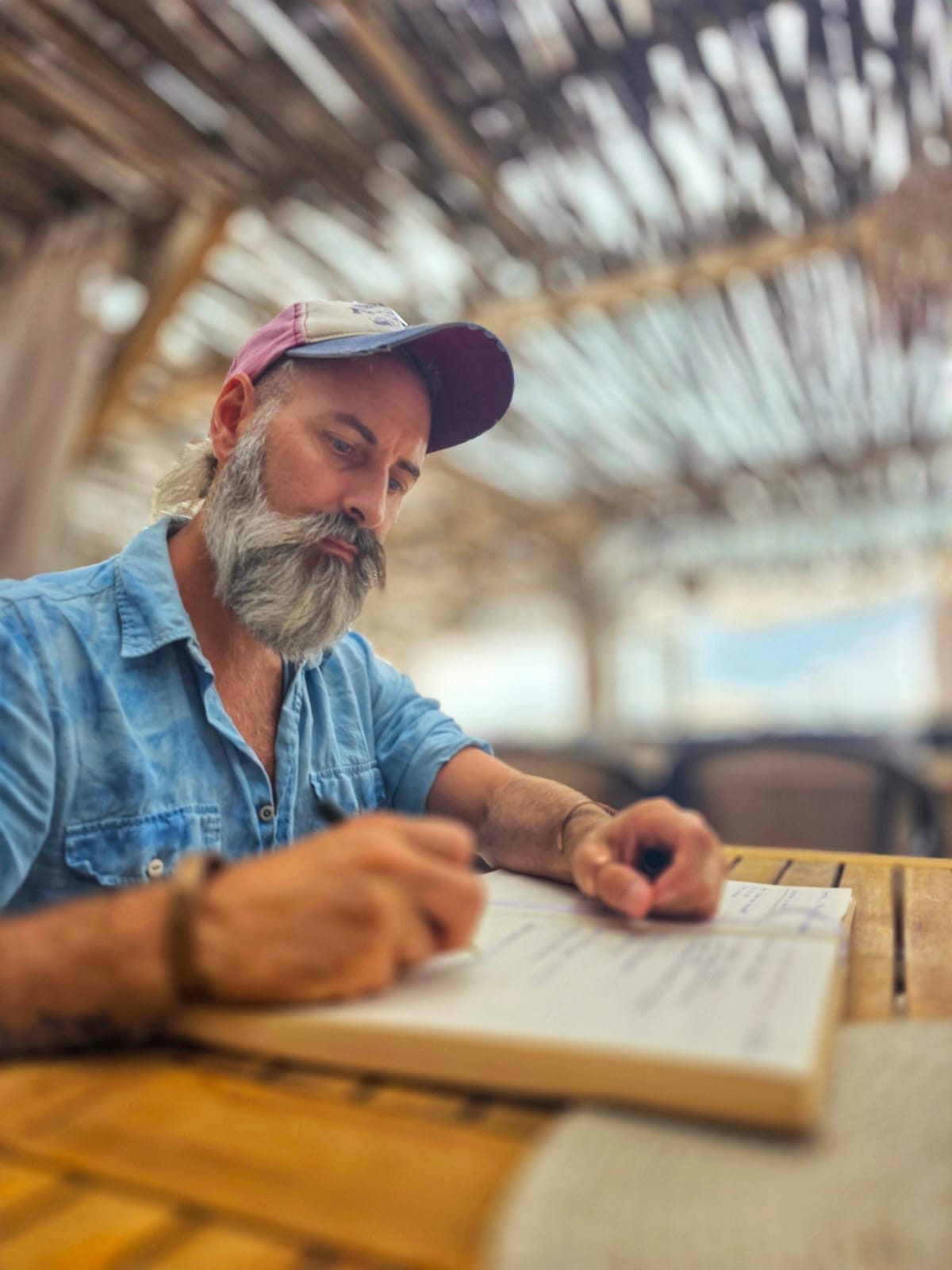 Andreas Hoiboom schreibt handschriftlich Wissen in ein Buch an einem Holztisch